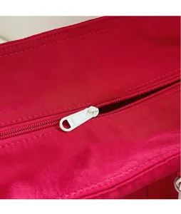 Gros plan détaillé de la tirette de fermeture SBS en métal sur un sac en tissu rouge