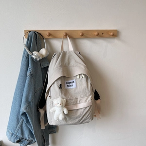 Detail of beige nylon backpack with cute bear pendant and square patch embroidery