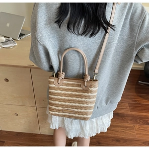 Detailed macro shot of beige and light brown striped woven straw bag with metal logo