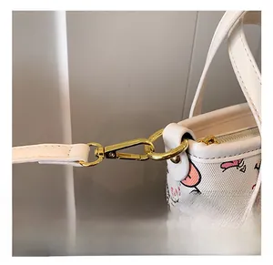 Detail of the high-quality gold metal hook and leather strap on a white graffiti tote bag
