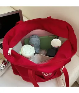 Intérieur spacieux du cabas en toile rouge montrant le rangement pour tablette et objets