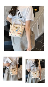 Detailed close-up of a cream cartoon graffiti bucket bag with Luck print and gold hardware