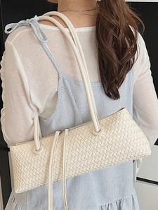 Fashionable creamy white woven underarm baguette bag with stylish leather tassels
