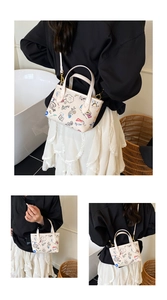 Detail shot of cute white bucket bag with colorful cartoon graffiti and gold hardware