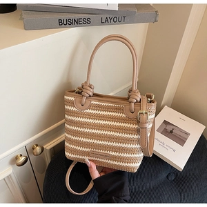 Close-up of woven straw tote bag featuring brown leather straps and striped texture