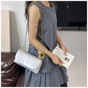 Sac argenté chic avec une poignée épingle à nourrice dorée et bandoulière sur le modèle