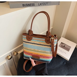 Detail of colorful woven bucket bag featuring striped pattern and leather straps