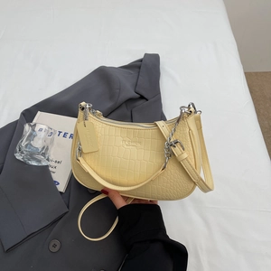 Detail of cream baguette bag with crocodile texture and silver metal chain strap