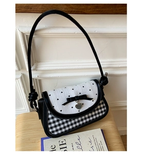 Detail of polka dot and checkered fabric handbag with black bow and heart-shaped charm
