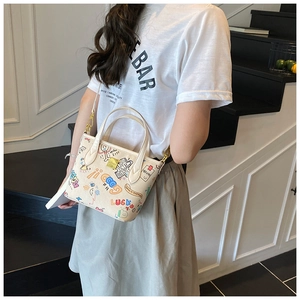Detail of cute cartoon graffiti handbag featuring colorful prints and gold metal hardware