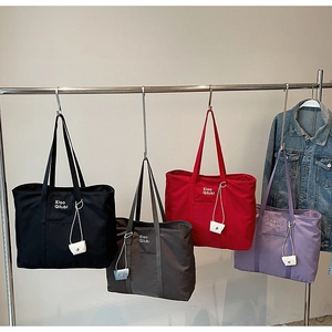 Détail de grands cabas en nylon en quatre couleurs avec mini-pochettes et longues anses