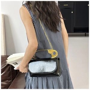 Détail du sac à main noir brillant avec poignée épingle de sûreté dorée et bandoulière