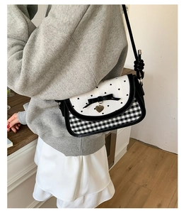 Detail of crossbody bag with black and white checkerboard pattern and bow decoration