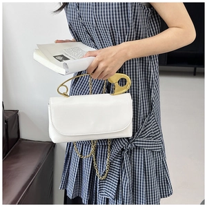 Détail d'un sac en cuir blanc avec poignée épingle à nourrice dorée et bandoulière
