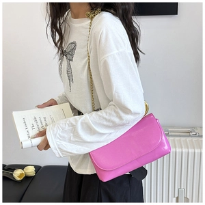 Détail du sac bandoulière en cuir verni rose fuchsia avec chaîne dorée épaisse