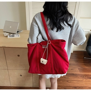 Détail du grand sac cabas en toile rouge avec bretelles et pendentif blanc décoratif