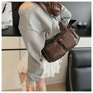 Detailed view of deep brown glossy leather shoulder bag with functional multi-pockets