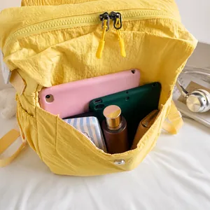 Detail view of the spacious front pocket of this yellow canvas backpack showing various items
