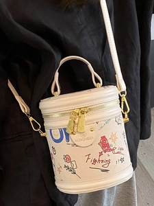 Minimalist beige bucket bag with artistic graffiti prints and golden hardware