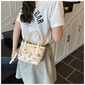 Detail view of cream doodle handbag with colorful cartoon prints and gold hardware
