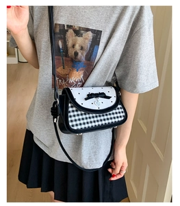Fashionable black and white checkered crossbody bag with bow and heart pendant on a model