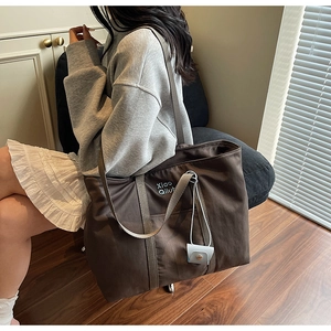 Détail d'un grand sac cabas marron café avec broderie et une petite pochette bleue