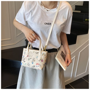 Detail of cream crossbody bucket bag with colorful cartoon graffiti and metal buckle