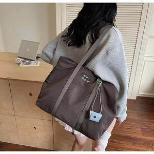 Détail du sac cabas marron café avec lettrage blanc et un mini accessoire de pochette bleue