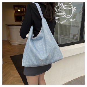 Detail of light blue denim tote bag showing its textured fabric and slouchy commuter style