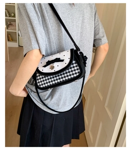 Detail of the heart-patterned crossbody bag with bow charm and gingham design