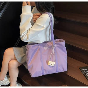 Détail du grand sac cabas en toile violette avec pendentif décoratif et imprimé lettrage