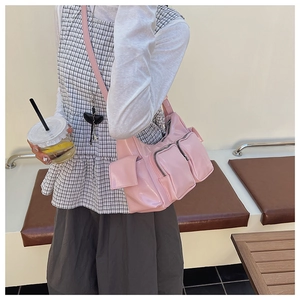 Detail of light pink multi-pocket shoulder bag in glossy PU leather with zippers