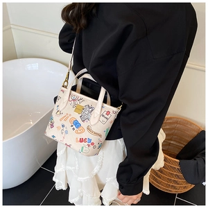 Detail of cute cream bucket bag with cartoon graffiti and premium metal hardware