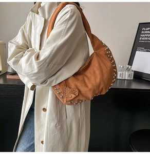 Sac hobo en daim marron avec détails de rivets argentés et motifs de clous en cœur