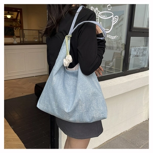 Close-up of light blue textured denim tote bag featuring a white tulip floral charm