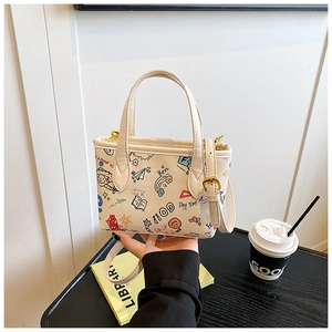 Detail of cute cream bucket bag featuring colorful cartoon doodles and adjustable strap