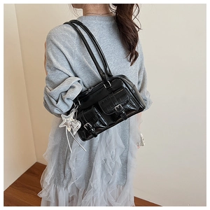 Détail du sac bandoulière noir texture crocodile avec breloques étoiles et doubles poches