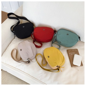 Minimalist nylon crossbody bags in five colors with adjustable straps on a white sofa