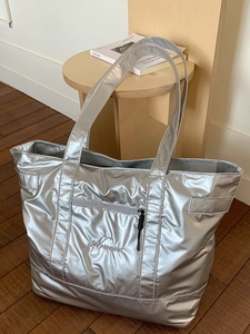 Metallic silver high-capacity gym tote bag with front zipper pocket and embroidery detail