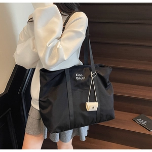 Détail du sac cabas en nylon noir avec une petite pochette beige et des bandoulières