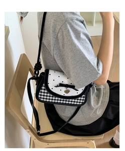 Detail of crossbody mini bag with black bow and heart print on a white flap