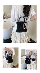 Black pleated bucket bag with pink pearl handle shown in various carrying styles