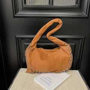 Détail d'un sac à bandoulière en daim orange avec rivets argentés sur marbre