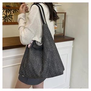 Detailed macro view of deep grey denim tote bag with glittering starry sequin texture