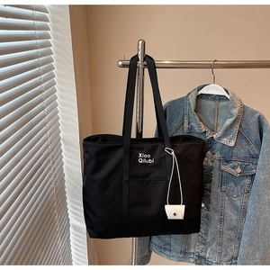 Détail du grand cabas en toile noire avec bandoulières et petite pochette blanche suspendue