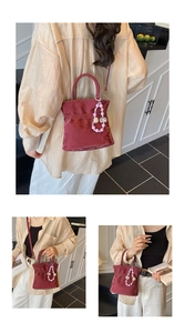 Detail of burgundy velvet handbag featuring soft pleated texture and pink pearl bow charm