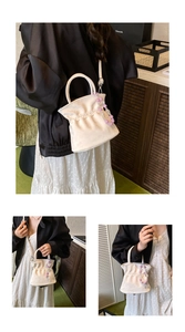 Detailed close-up of cream white pleated bucket bag with purple pearl bead charm