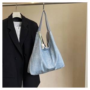 Detail of light blue glittery hobo tote bag featuring a white tulip charm and shoulder strap