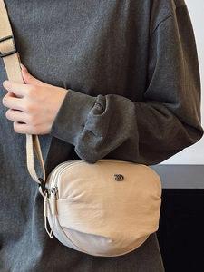 Minimalist beige nylon crossbody bag with adjustable strap and dual zipper compartments