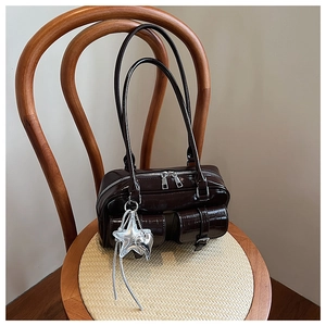 Vue détaillée du sac Boston marron brillant avec pendentif étoile et poches frontales